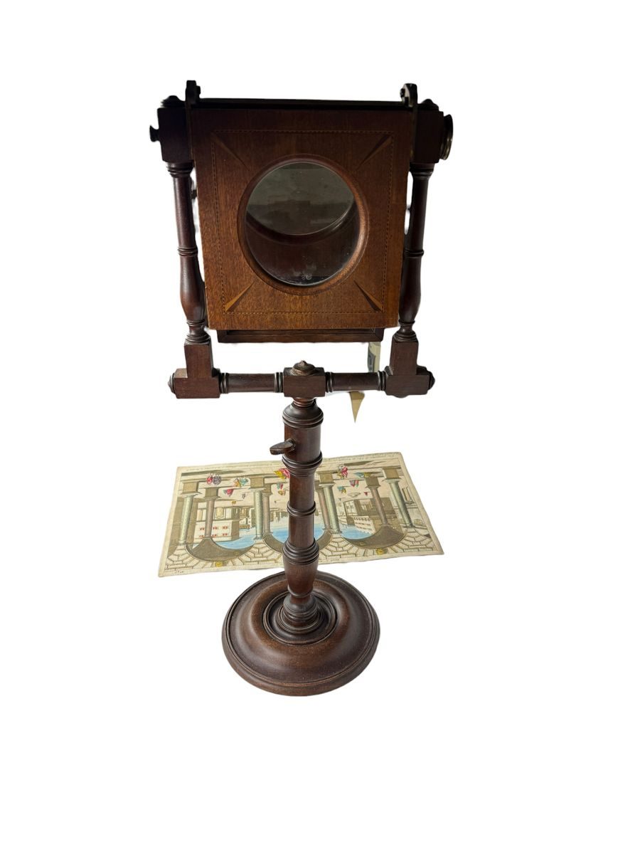 A zograscope with a vue d'optique beneath the lens: the print lies flat, the viewer looks down through the glass.